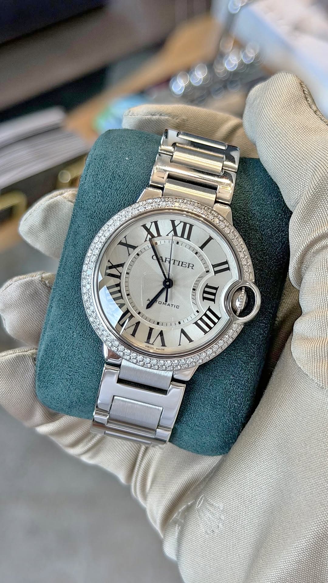 Gloved hands presenting a diamond-bezel Cartier Ballon Bleu