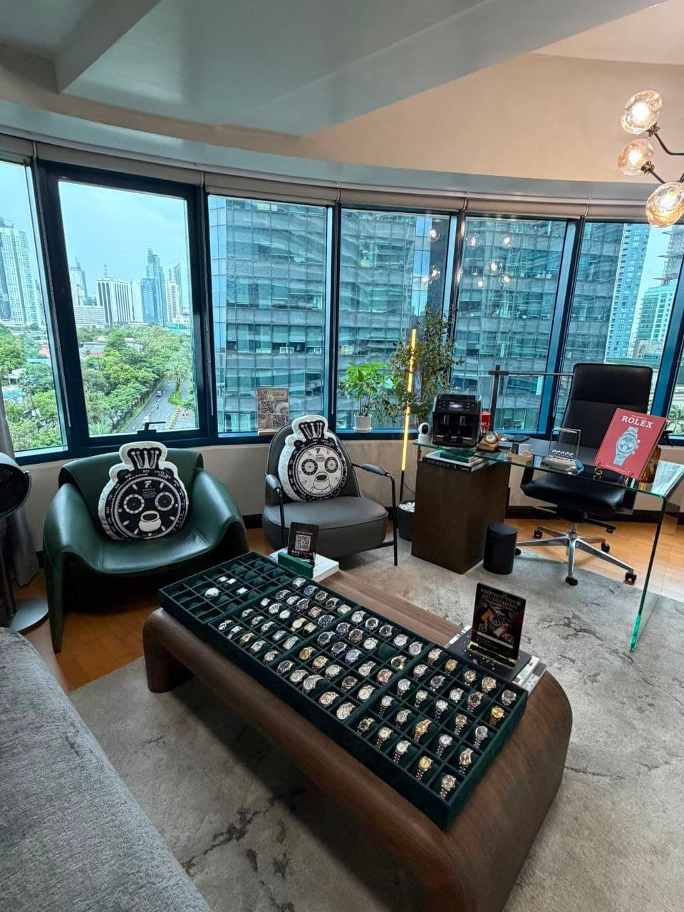 The Timeless Elegance showroom in Rockwell, Makati — watch trays laid out on the centre table, Makati skyline through the windows